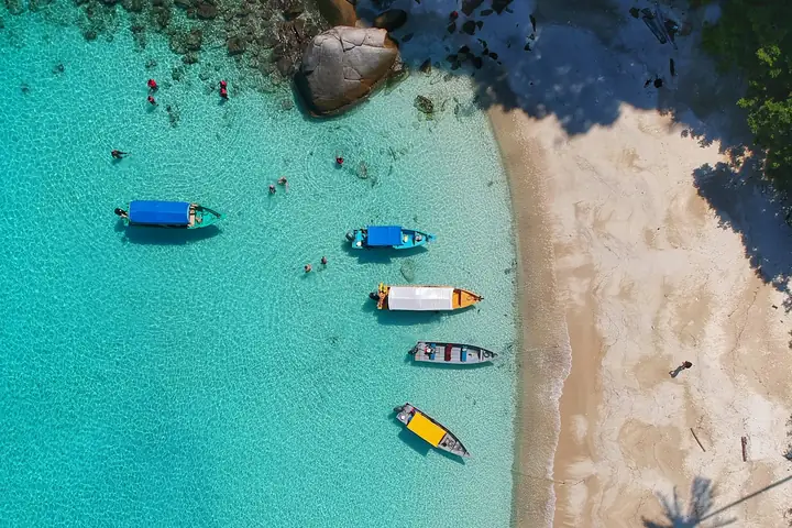 Baia con acqua turchese e barche vista dall’alto